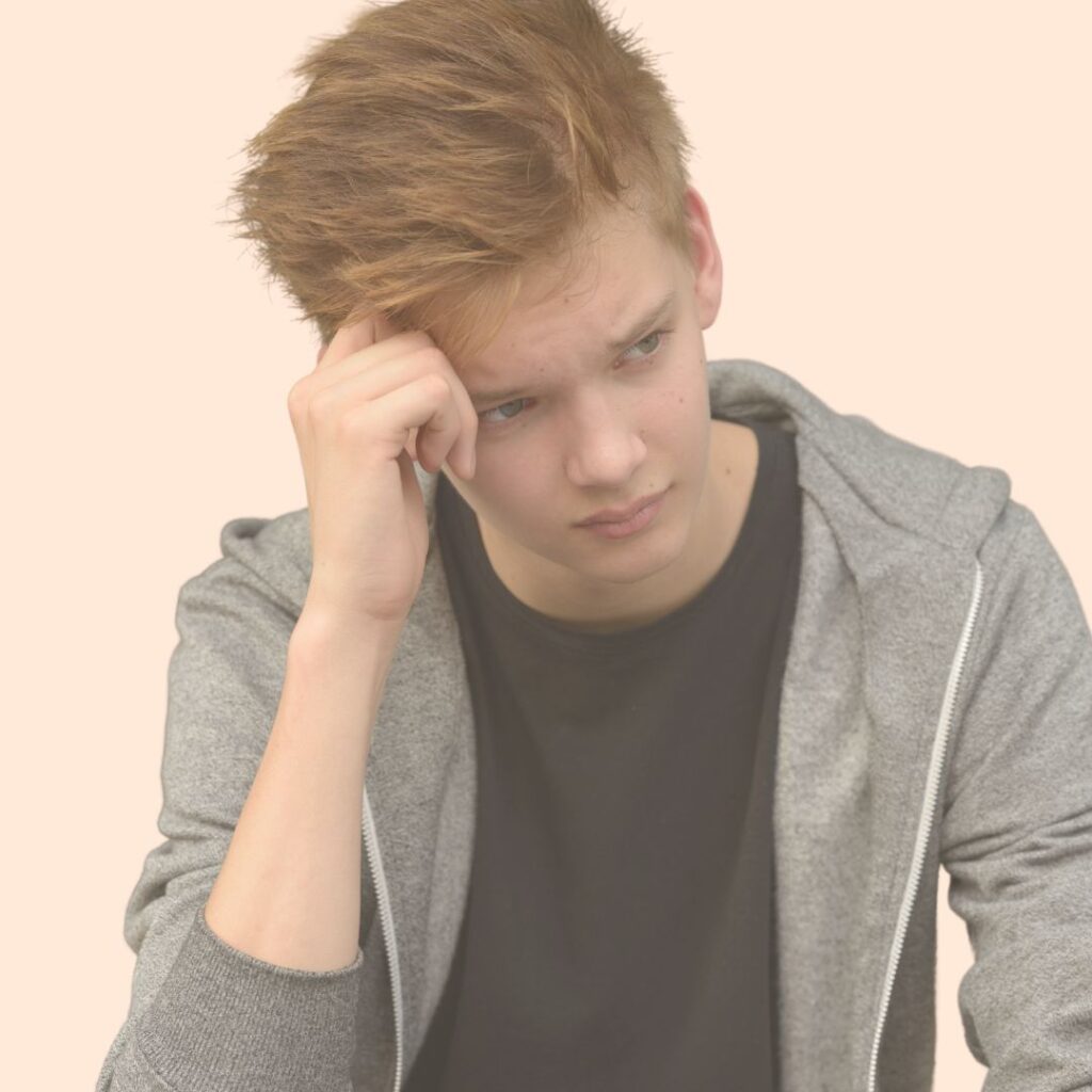 Adolescent roux qui se tient la tête avec sa main droite, il a l'air inquiet